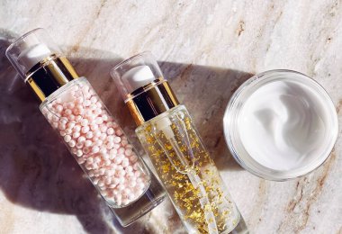 Cilt bakım ürünleri, yüz kremi kavanozu ve şişelerde altın serumu emülsiyonu, düz görünüm güzellik ürünü.