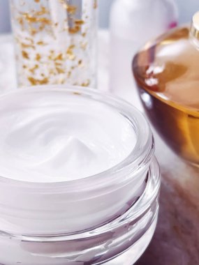 Cilt bakım ürünleri, yüz kremi nemlendirici kavanozu, altın serum emülsiyon şişeleri, yakın çekim güzellik ürünü.