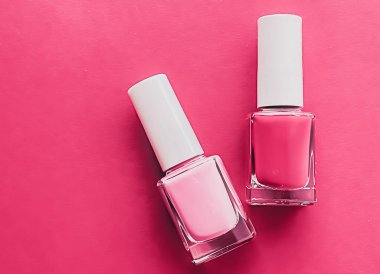 Gül arka planında pembe oje şişeleri, manikür ve güzellik kozmetik konsepti