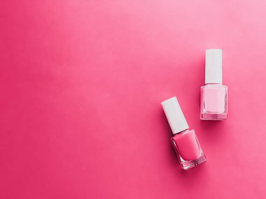 Gül arka planında pembe oje şişeleri, manikür ve güzellik kozmetik konsepti