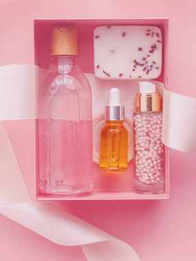 Pembe arka planda güzellik kutusu aboneliği, spa ve makyaj ürünleri, düz dizayn, doğal kozmetik hediye teslim konsepti