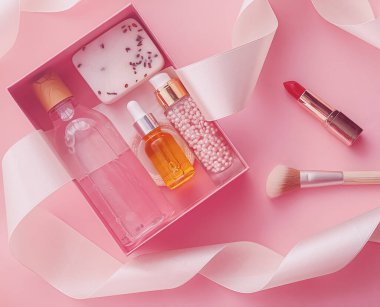 Pembe arka planda güzellik kutusu aboneliği, spa ve makyaj ürünleri, düz dizayn, doğal kozmetik hediye teslim konsepti