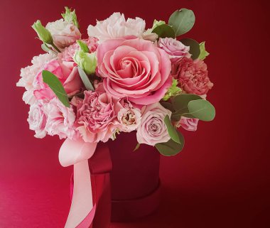 Kırmızı arka planda güzel bir çiçek kutusu, çiçek buketi bayram hediyesi olarak, lüks çiçek tasarımı konsepti