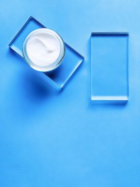 Cam ve mavi arka planda yüz kremi kavanozu, güzellik ürünü ve cilt bakımı, kozmetik bilimi konsepti