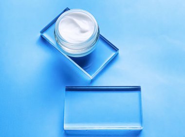 Cam ve mavi arka planda yüz kremi kavanozu, güzellik ürünü ve cilt bakımı, kozmetik bilimi konsepti