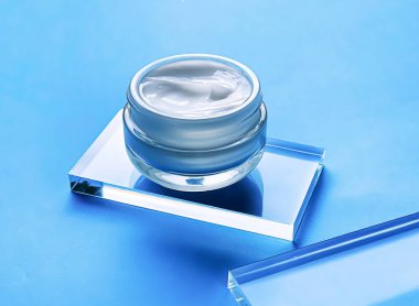 Cam ve mavi arka planda yüz kremi kavanozu, güzellik ürünü ve cilt bakımı, kozmetik bilimi konsepti