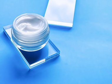 Cam ve mavi arka planda yüz kremi kavanozu, güzellik ürünü ve cilt bakımı, kozmetik bilimi konsepti