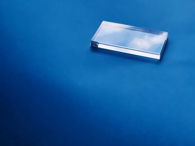 Mavi arkaplanda şeffaf cam aygıt, geleceğin teknolojisi ve soyut ekran modelleme konsepti