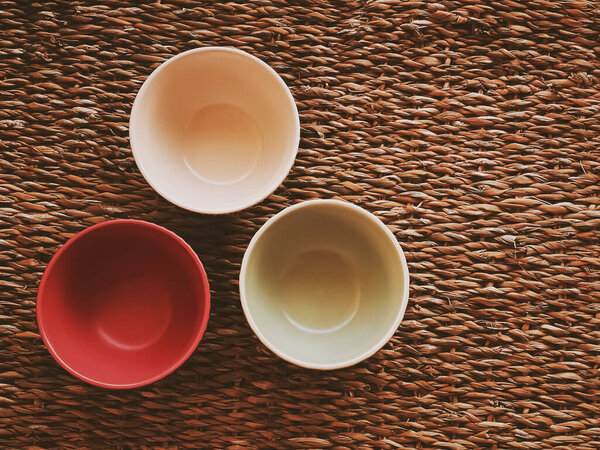 Small empty ceramic measure bowls on rustic wicker background, food preparation flatlay and cooking design concept