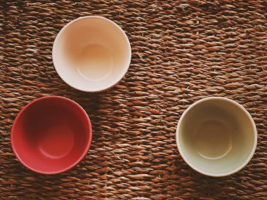Small empty ceramic measure bowls on rustic wicker background, food preparation flatlay and cooking design concept