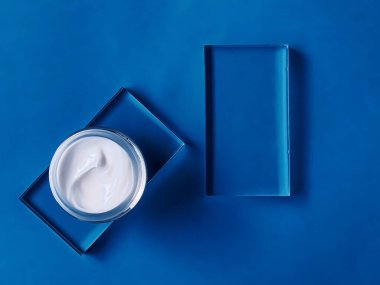 Cam ve mavi arka planda yüz kremi kavanozu, güzellik ürünü ve cilt bakımı, kozmetik bilimi konsepti