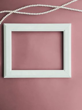 Horizontal art frame and pearl jewellery on blush pink background as flatlay design, artwork print or photo album concept