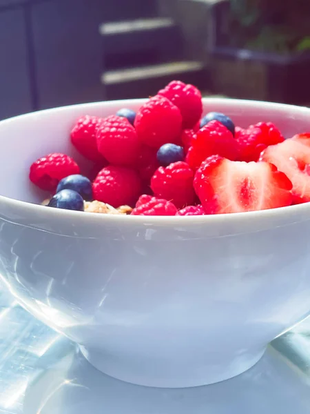 屋外庭園でのシリアル ヨーグルト イチゴ ラズベリー ブルーベリーとおいしい朝食 健康的な食べ物と食事 — ストック写真