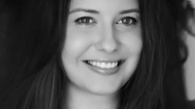 Rüzgar gibi esen saçları olan mutlu genç bir kadın gülümseyen siyah beyaz bir portre, uzun sağlıklı saçlar ve saç bakım konsepti.