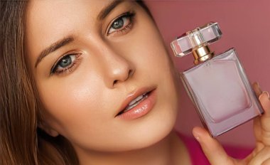 Parfüm, güzellik ürünü ve kozmetik modeli pembe arka planda yüz portresi, çiçek kokulu parfüm şişesi tutan güzel kadın, moda ve makyaj konsepti.