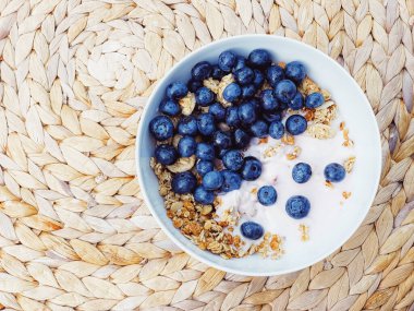 Sağlıklı kahvaltı ve sabah yemeği olarak yaban mersinli yoğurt kasesi, tatlı yemek ve organik meyve, diyet ve beslenme konsepti