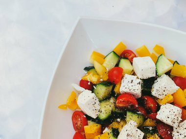 Fresh vegetable greek salad with cherry tomatoes, bell pepper, cucumber, feta cheese, olive oil and seasonal spices, healthy food diet and delicious meal recipe concept