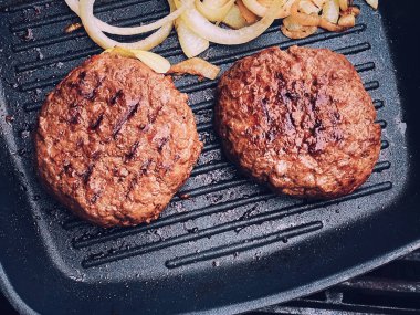 Cooking minced beef burger on cast iron grill skillet outdoors, red meat on frying pan, grilling food in the garden, English countryside living concept