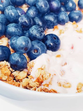 Sağlıklı kahvaltı ve sabah yemeği olarak yaban mersinli yoğurt kasesi, tatlı yemek ve organik meyve, diyet ve beslenme konsepti