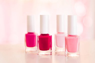Cazibeli arka planda pembe ve kırmızı oje gölgeleri, manikür ve pedikür için tırnak cilası şişeleri, lüks güzellik kozmetikleri ve makyaj reklamı.