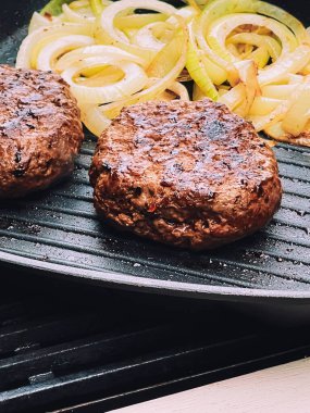 Cooking minced beef burger on cast iron grill skillet outdoors, red meat on frying pan, grilling food in the garden, English countryside living concept