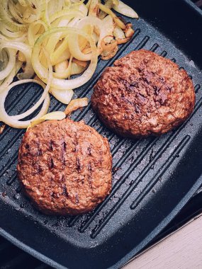 Cooking minced beef burger on cast iron grill skillet outdoors, red meat on frying pan, grilling food in the garden, English countryside living concept