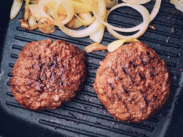 Cooking minced beef burger on cast iron grill skillet outdoors, red meat on frying pan, grilling food in the garden, English countryside living concept