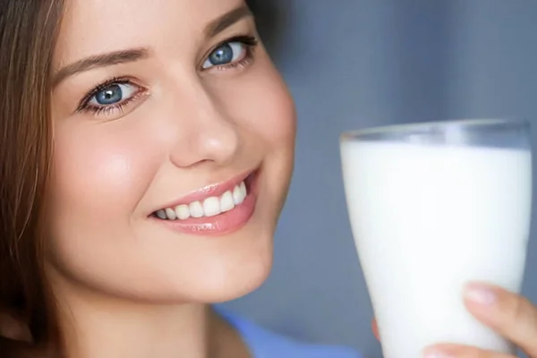 Happy young woman with glass of milk or protein milk shake, healthy cocktail drink for diet and wellness concept