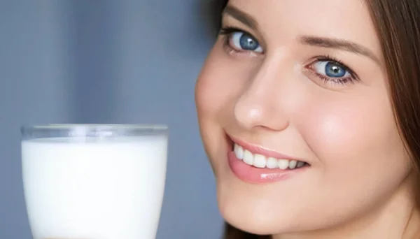 Happy young woman with glass of milk or protein milk shake, healthy cocktail drink for diet and wellness concept