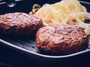 Cooking minced beef burger on cast iron grill skillet outdoors, red meat on frying pan, grilling food in the garden, English countryside living concept