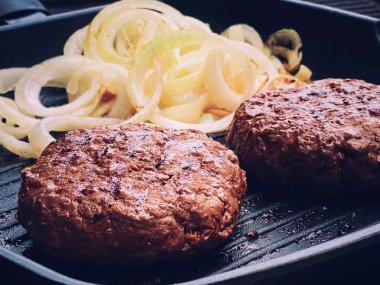 Cooking minced beef burger on cast iron grill skillet outdoors, red meat on frying pan, grilling food in the garden, English countryside living concept
