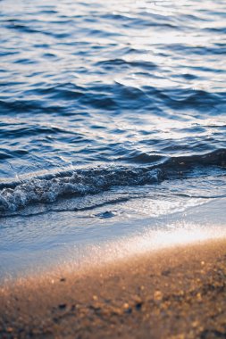 Blue sea waves and golden sand in sunshine glow at sunset, sandy beach and coastal nature concept