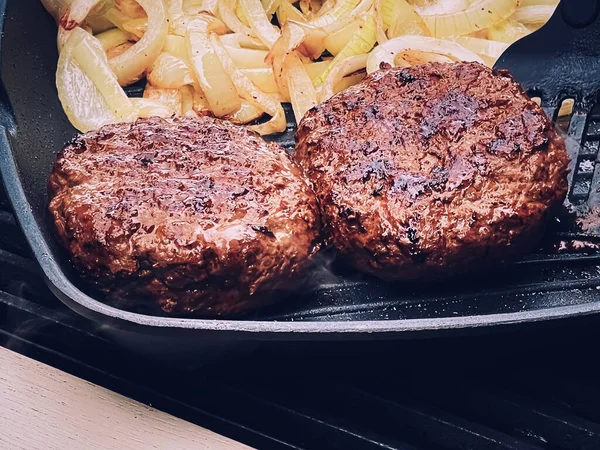 Cooking minced beef burger on cast iron grill skillet outdoors, red meat on frying pan, grilling food in the garden, English countryside living concept