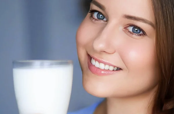 Happy young woman with glass of milk or protein milk shake, healthy cocktail drink for diet and wellness concept