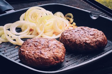 Cooking minced beef burger on cast iron grill skillet outdoors, red meat on frying pan, grilling food in the garden, English countryside living concept