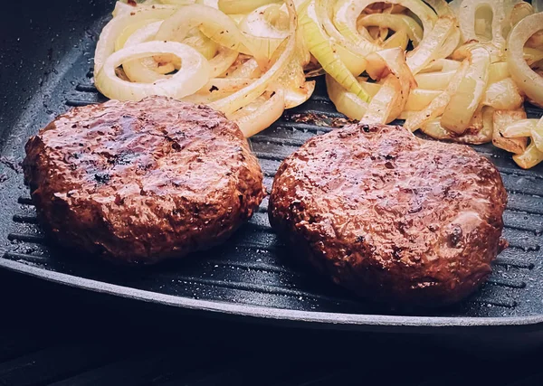 Cooking minced beef burger on cast iron grill skillet outdoors, red meat on frying pan, grilling food in the garden, English countryside living concept