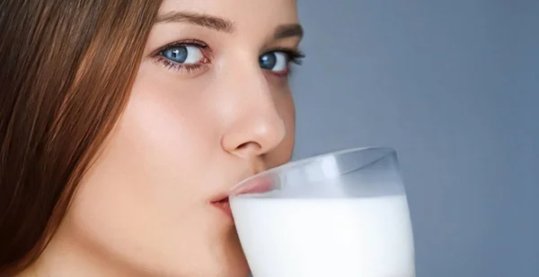 Happy young woman drinking milk or protein milk shake cocktail, healthy drink for diet and wellness concept