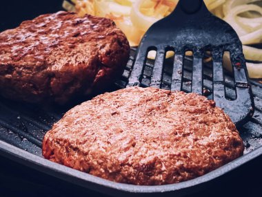Cooking minced beef burger on cast iron grill skillet outdoors, red meat on frying pan, grilling food in the garden, English countryside living concept