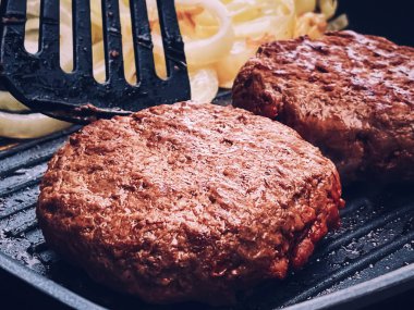 Cooking minced beef burger on cast iron grill skillet outdoors, red meat on frying pan, grilling food in the garden, English countryside living concept