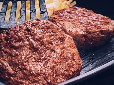 Cooking minced beef burger on cast iron grill skillet outdoors, red meat on frying pan, grilling food in the garden, English countryside living concept