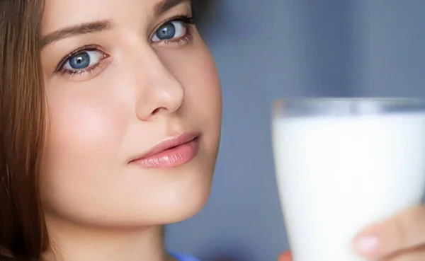 Happy young woman with glass of milk or protein milk shake, healthy cocktail drink for diet and wellness concept