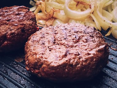Cooking minced beef burger on cast iron grill skillet outdoors, red meat on frying pan, grilling food in the garden, English countryside living concept