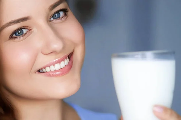 Happy young woman with glass of milk or protein milk shake, healthy cocktail drink for diet and wellness concept