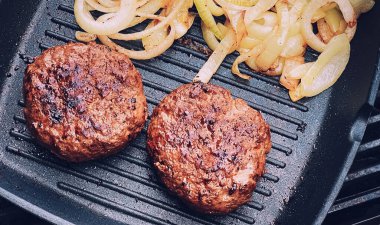 Cooking minced beef burger on cast iron grill skillet outdoors, red meat on frying pan, grilling food in the garden, English countryside living concept