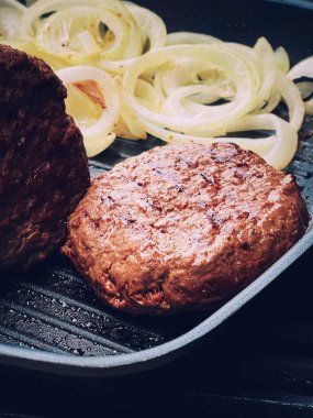Cooking minced beef burger on cast iron grill skillet outdoors, red meat on frying pan, grilling food in the garden, English countryside living concept