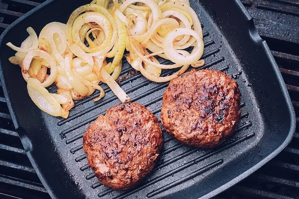 Cooking minced beef burger on cast iron grill skillet outdoors, red meat on frying pan, grilling food in the garden, English countryside living concept