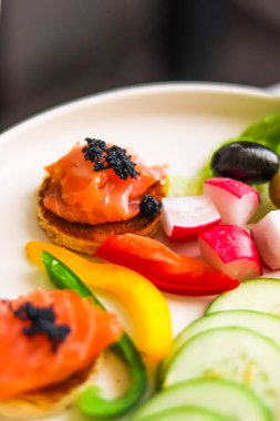 Somon, siyah havyar ve konukseverlik ve gastronomi için taze sebze dilimlenmiş aperatif tabağı.