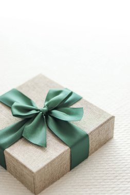 Holiday present and luxury online shopping delivery, wrapped linen gift box with green ribbon on bed in bedroom, chic countryside style, close-up
