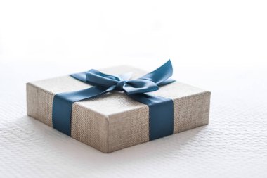 Holiday present and luxury online shopping delivery, wrapped linen gift box with blue ribbon on bed in bedroom, chic countryside style, close-up