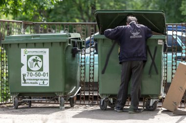 Poor man searching in garbage, Vologda, Russia clipart